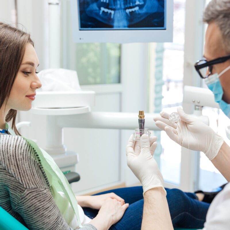 dentist holding a dental implant for a patient in a dentist chair