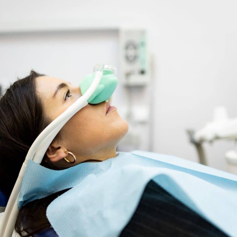 a woman in a dental chair with a mask on her face